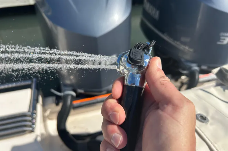 Slide: The Image of Hand holding a hose spraying water on a 2020 Grady-White Canyon 306 boat. - 17