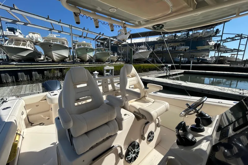 Slide: The Image of 2020 Grady-White Canyon 306 boat interior with helm and docked boats in background. - 22