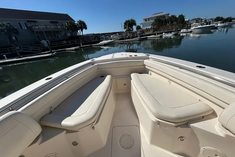 Slide: The Image of 2020 Grady-White Canyon 306 boat interior at a marina, showcasing seating and calm waters. - 35