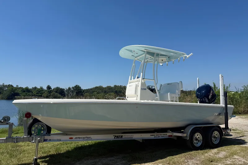 The Image of 2026 Pathfinder 2200 TRS boat on trailer by a lake under clear blue sky. - 0