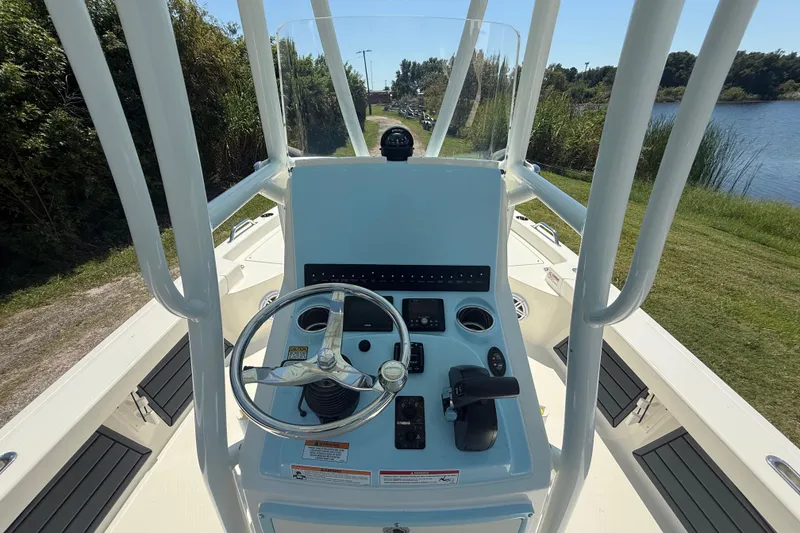 Slide: The Image of 2026 Pathfinder 2200 TRS boat console with steering wheel and controls, near a lake. - 14