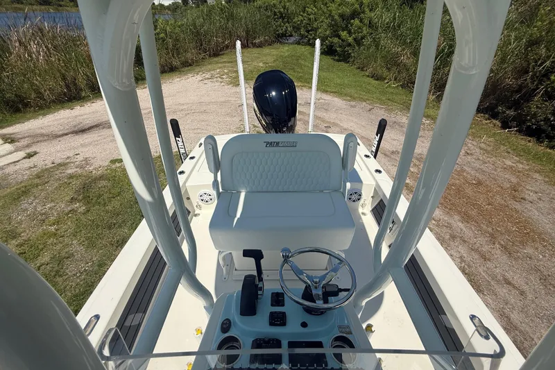 Slide: The Image of 2026 Pathfinder 2200 TRS boat interior with steering wheel and seating, parked near water. - 21
