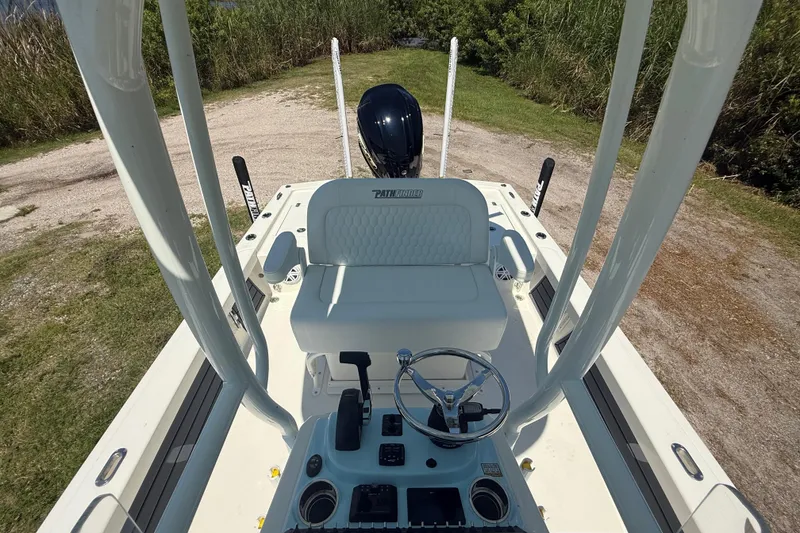 Slide: The Image of 2026 Pathfinder 2200 TRS boat interior with steering wheel and seating, parked on grassy area. - 22