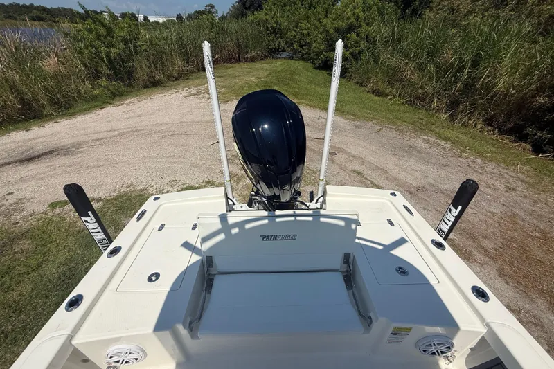 Slide: The Image of 2026 Pathfinder 2200 TRS boat with motor, parked on grassy terrain near water. - 24