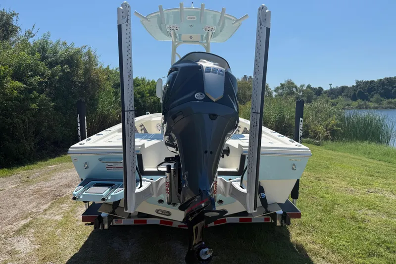 Slide: The Image of 2026 Pathfinder 2200 TRS boat with motor, parked near a lake on a sunny day. - 3