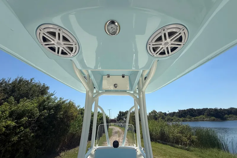 Slide: The Image of 2026 Pathfinder 2200 TRS boat with speakers, viewed from below, near a scenic waterway. - 33