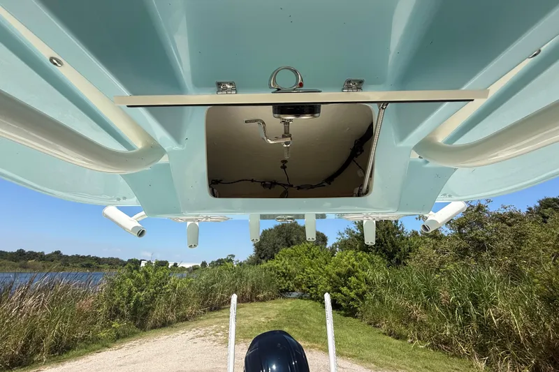 Slide: The Image of 2026 Pathfinder 2200 TRS boat underside view with open hatch, near a scenic waterway. - 36