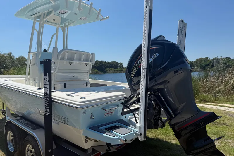 Slide: The Image of 2026 Pathfinder 2200 TRS boat with Yamaha engine, parked near a serene lake. - 6