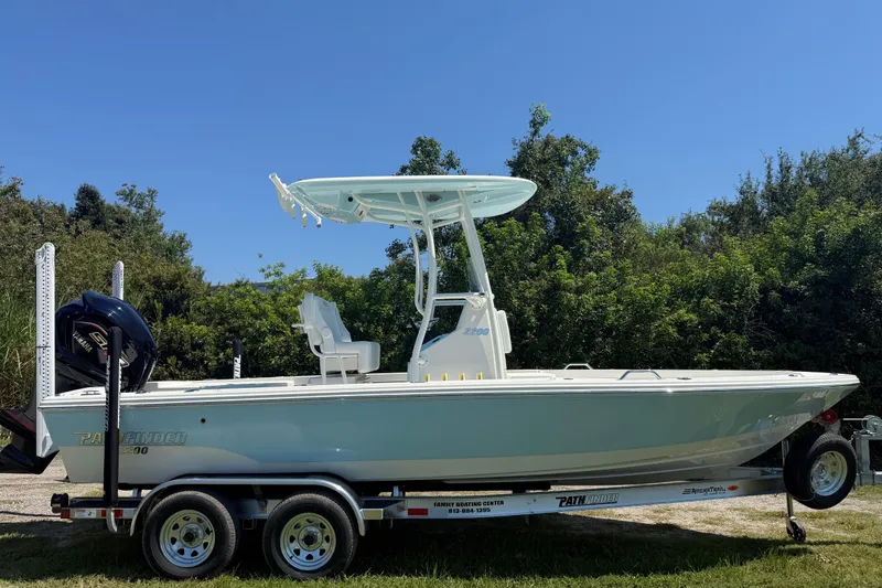 Slide: The Image of 2026 Pathfinder 2200 TRS boat on trailer, parked outdoors with lush greenery background. - 8