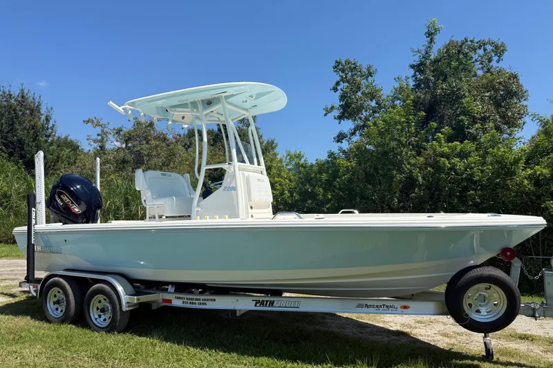 Slide: The Image of 2026 Pathfinder 2200 TRS boat on trailer, parked outdoors with lush greenery background. - 9