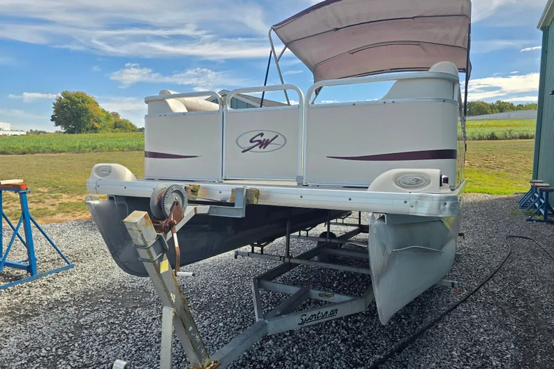 Slide: The Image of Sweetwater 2019RE pontoon boat, 2003 model, with red cover, parked on gravel. - 2