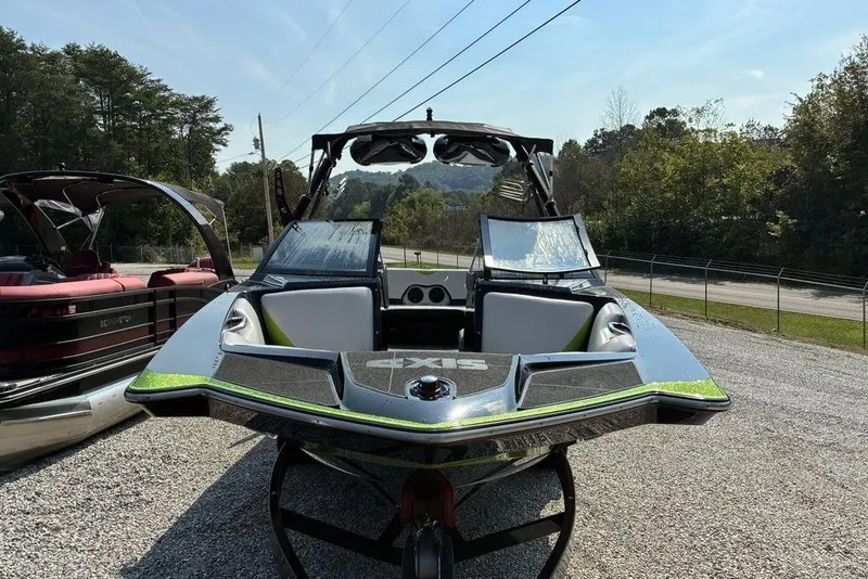 The Image of 2014 Axis A24 boat with sleek design, parked on gravel, surrounded by trees. - 1