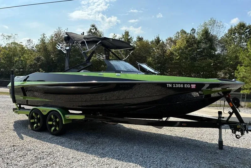 Slide: The Image of 2014 Axis A24 boat with green and black design on a trailer, parked outdoors. - 6