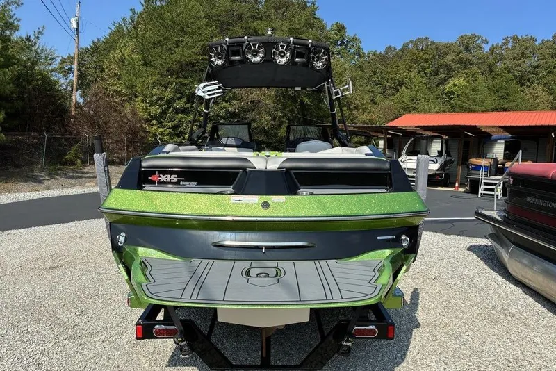 Slide: The Image of 2014 Axis A24 boat with green accents, parked outdoors on gravel. - 7