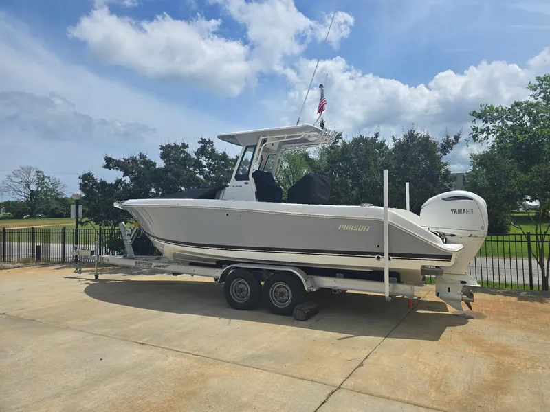 The Image of 2025 Pursuit S 248 Sport boat on trailer, parked outdoors under a partly cloudy sky. - 0