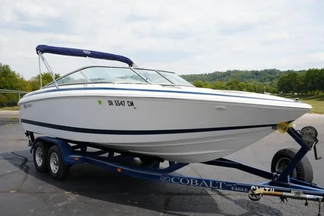 Slide: The Image of 2000 Cobalt 226 boat on trailer, parked outdoors with scenic background. - 1