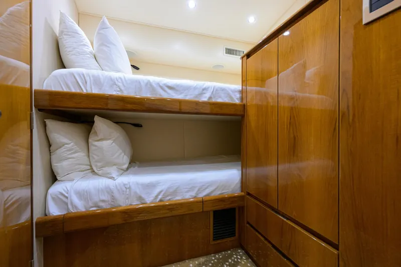 Slide: The Image of Bunk beds in 2014 Viking 76 Enclosed Bridge Convertible yacht cabin, featuring wooden cabinetry. - 30