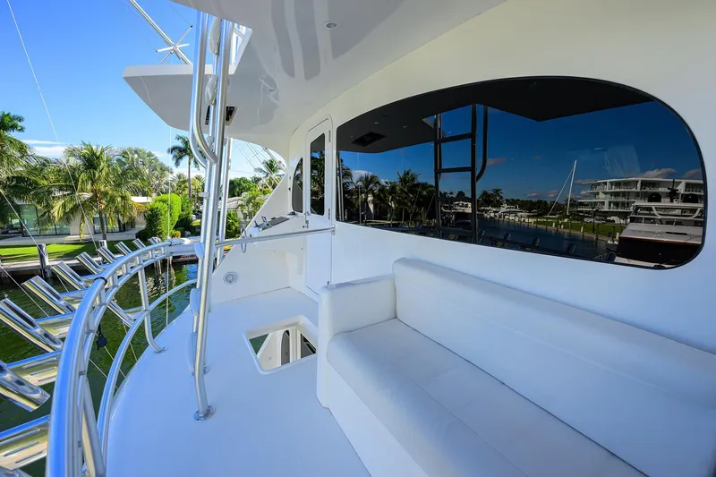 Slide: The Image of 2014 Viking 76 Enclosed Bridge Convertible yacht deck with white seating and marina view. - 46