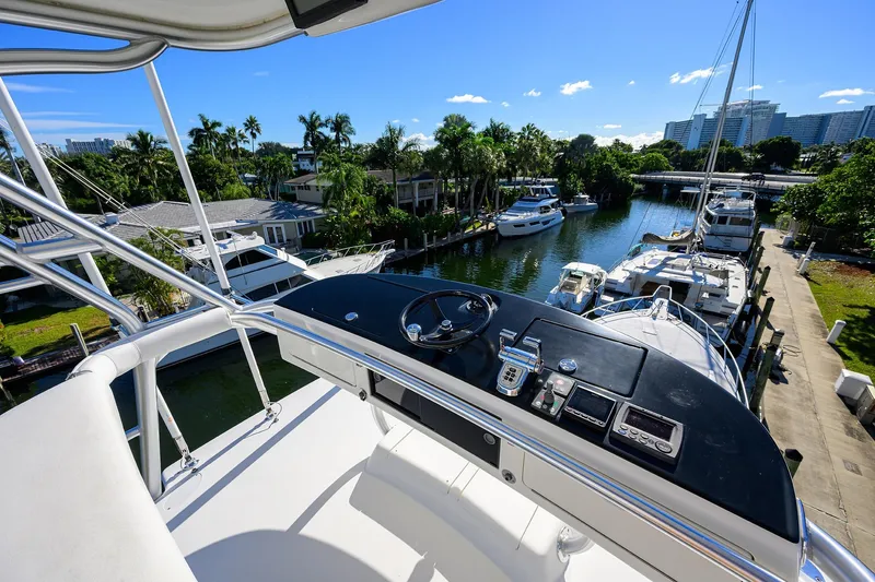 Slide: The Image of 2014 Viking 76 Enclosed Bridge Convertible yacht overlooking marina with palm trees and clear sky. - 51