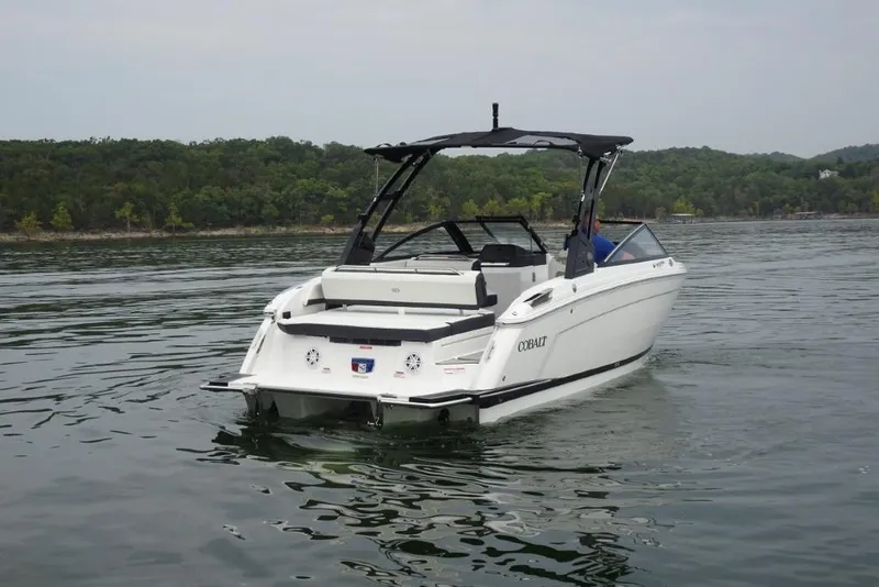 Slide: The Image of 2026 Cobalt R6 boat cruising on a serene lake with lush green shoreline. - 2