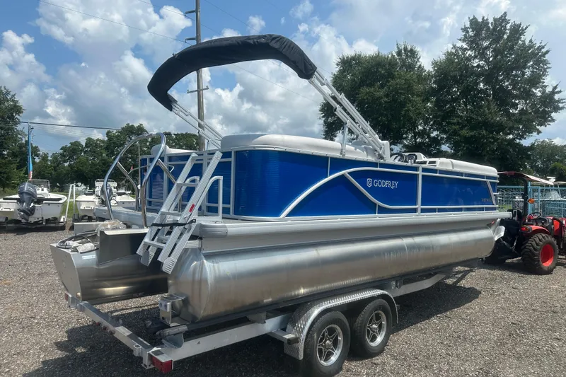 Slide: The Image of 2024 Godfrey SWEETWATER 2286 SB pontoon boat on trailer, blue and silver design. - 5