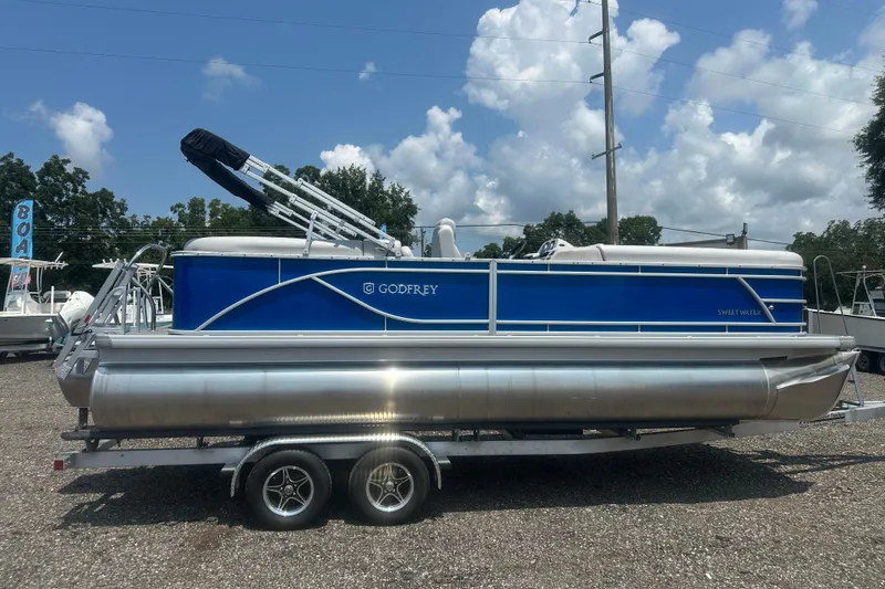 Slide: The Image of 2024 Godfrey SWEETWATER 2286 SB pontoon boat on trailer, blue and silver design. - 6
