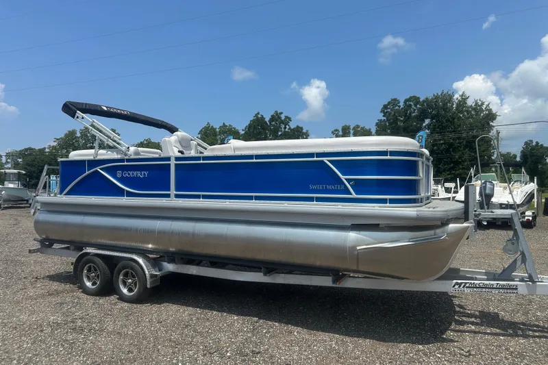 Slide: The Image of 2024 Godfrey SWEETWATER 2286 SB pontoon boat on trailer, blue and silver design. - 7