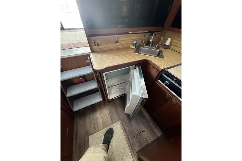 Slide: The Image of 1978 Silverton F32 boat kitchen with open fridge, sink, and wooden cabinetry. - 16