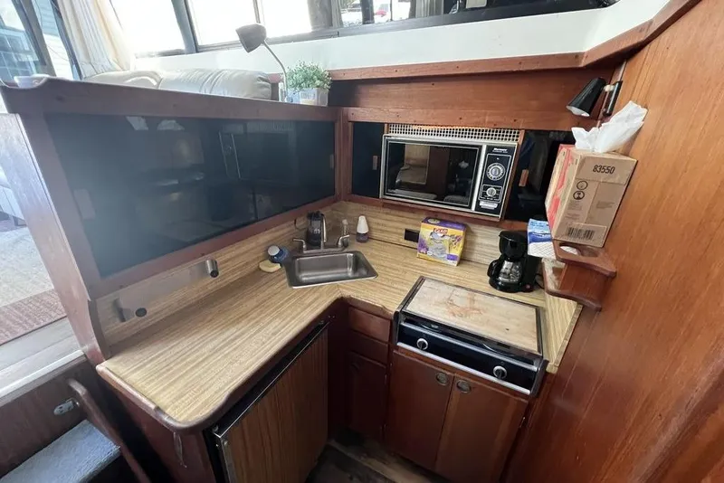 Slide: The Image of 1978 Silverton F32 boat kitchen with sink, microwave, and wooden cabinetry. - 17