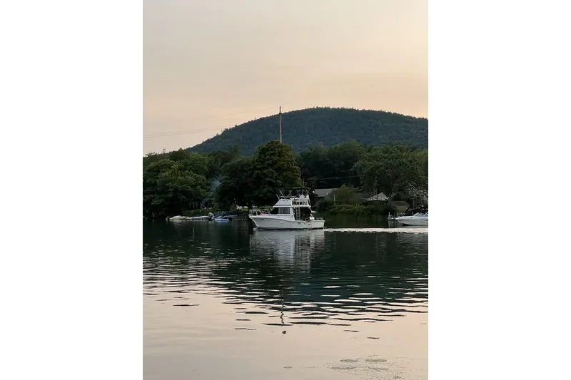 Slide: The Image of 1978 Silverton F32 boat cruising on a serene lake with a forested hill backdrop. - 4