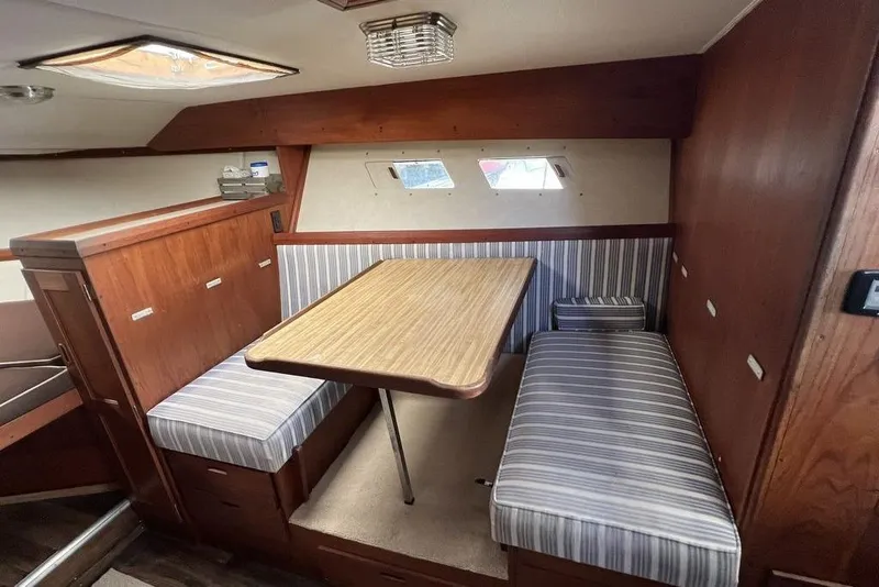 Slide: The Image of 1978 Silverton F32 boat interior with wood paneling and striped seating in dining area. - 13