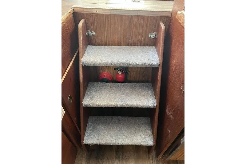 Slide: The Image of Carpeted wooden steps inside a 1978 Silverton F32 boat, with a fire extinguisher underneath. - 19