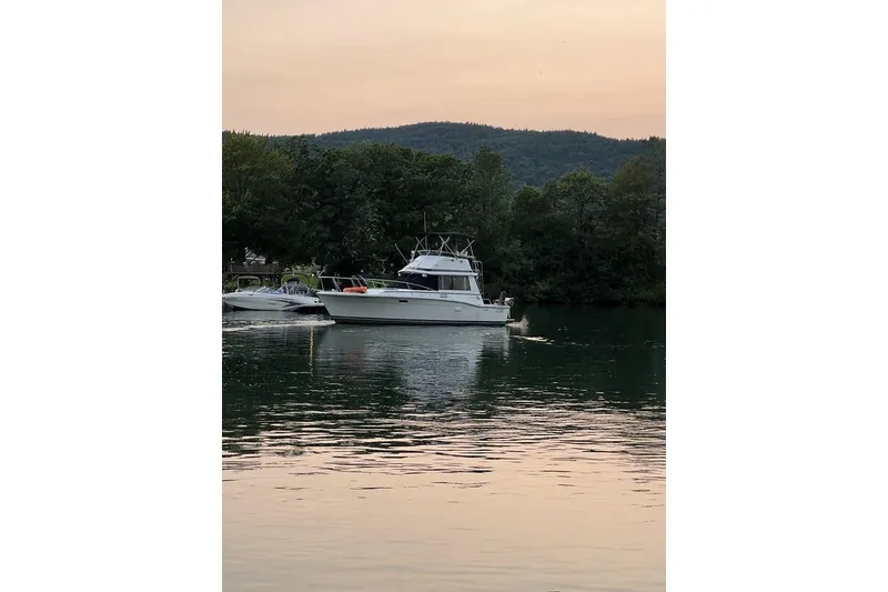 Slide: The Image of 1978 Silverton F32 boat on a serene lake with forested hills in the background. - 6