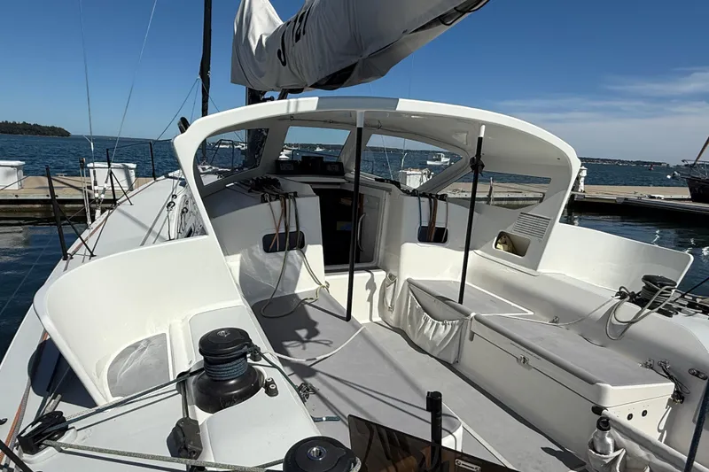 Slide: The Image of 2018 J Boats J/121 sailboat cockpit with winches, ropes, and seating, docked by the sea. - 10