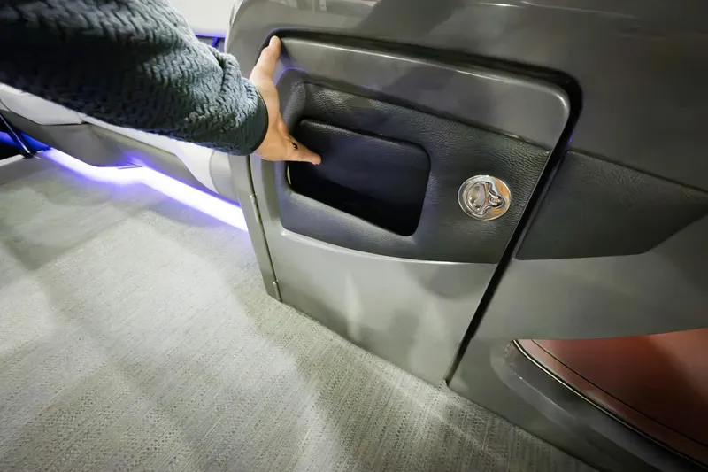 Slide: The Image of Hand opening storage compartment on 2026 Godfrey Monaco 255 Split Bench boat. - 27