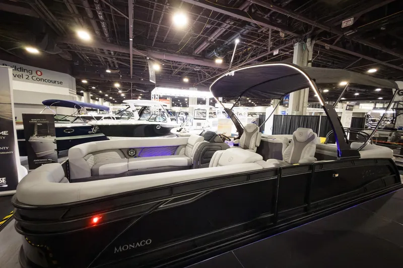 Slide: The Image of 2026 Godfrey Monaco 255 Split Bench pontoon boat displayed indoors at a boat show. - 7