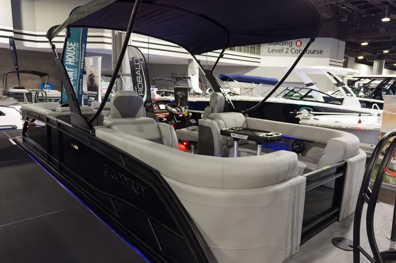 Slide: The Image of 2026 Godfrey Monaco 255 Split Bench pontoon boat displayed at an indoor boat show. - 8
