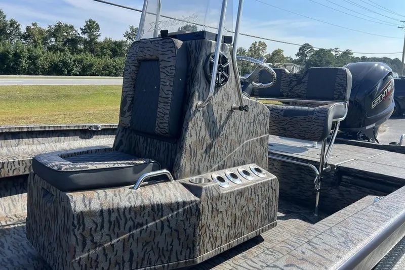 Slide: The Image of 2026 Xpress H22 boat interior with camouflage design and seating, featuring a powerful outboard motor. - 10