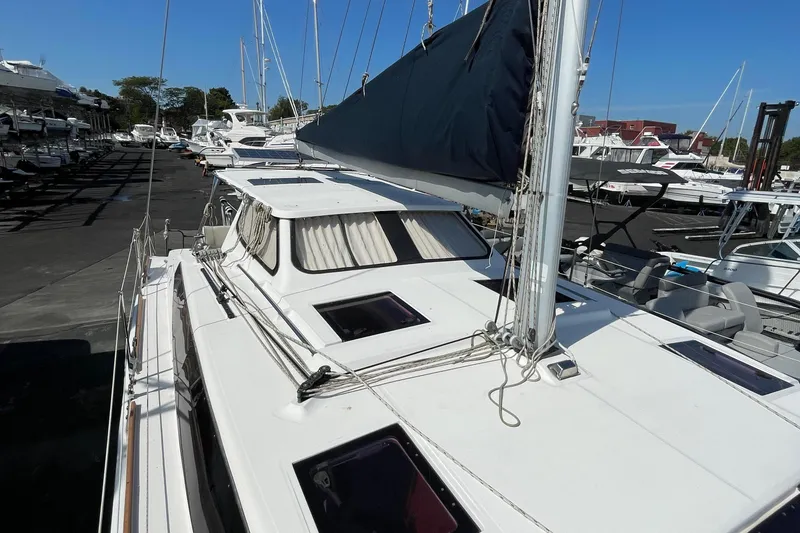 Slide: The Image of 2013 Gemini Legacy sailboat docked in a marina, featuring a sleek white design and covered sails. - 12