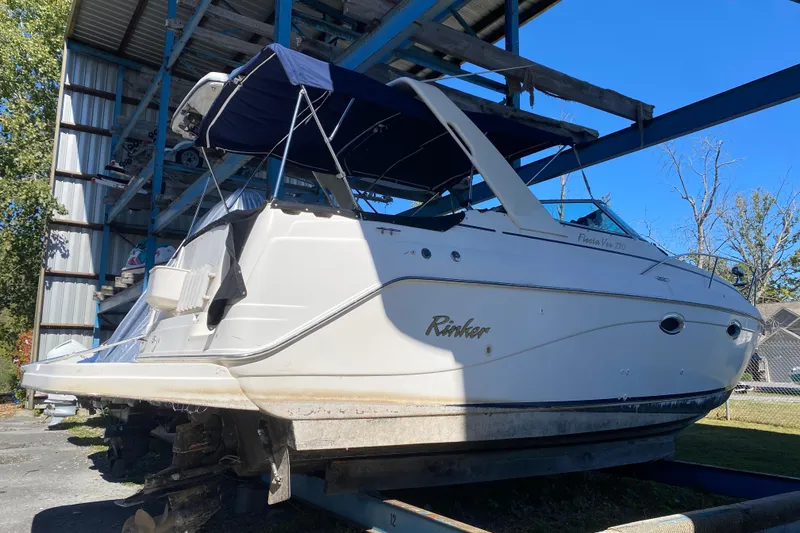 The Image of 2003 Rinker Fiesta Vee 270 boat stored on a rack under a metal roof. - 0
