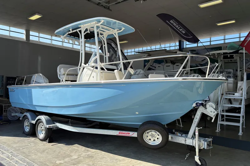 The Image of 2026 Boston Whaler 210 Montauk boat in showroom, light blue hull, on a trailer. - 0