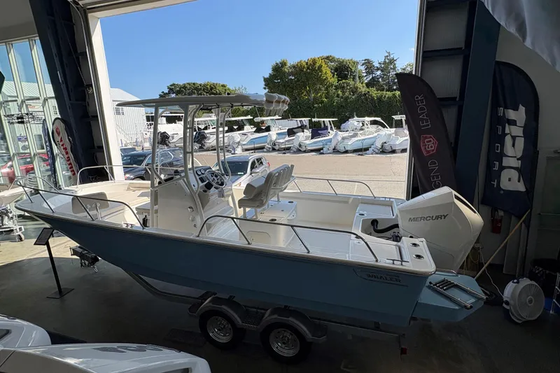Slide: The Image of 2026 Boston Whaler 210 Montauk boat in showroom, featuring Mercury engine and sleek design. - 16
