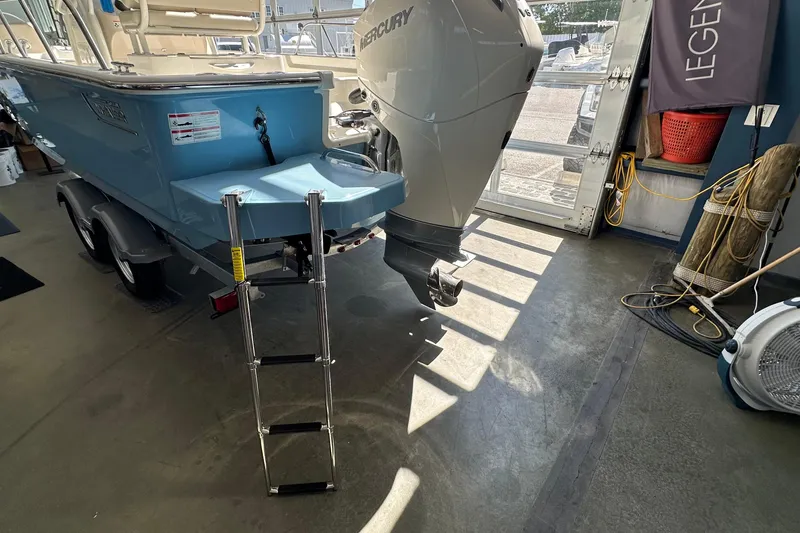 Slide: The Image of 2026 Boston Whaler 210 Montauk boat with Mercury engine and ladder in a showroom. - 3