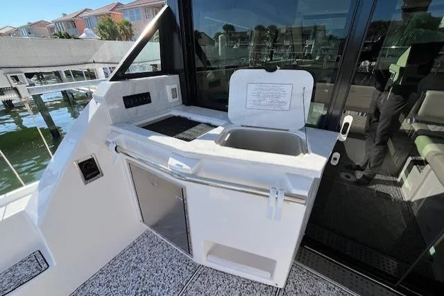Slide: The Image of 2022 Regal 38 XO yacht kitchenette with sink and grill, dockside view. - 14