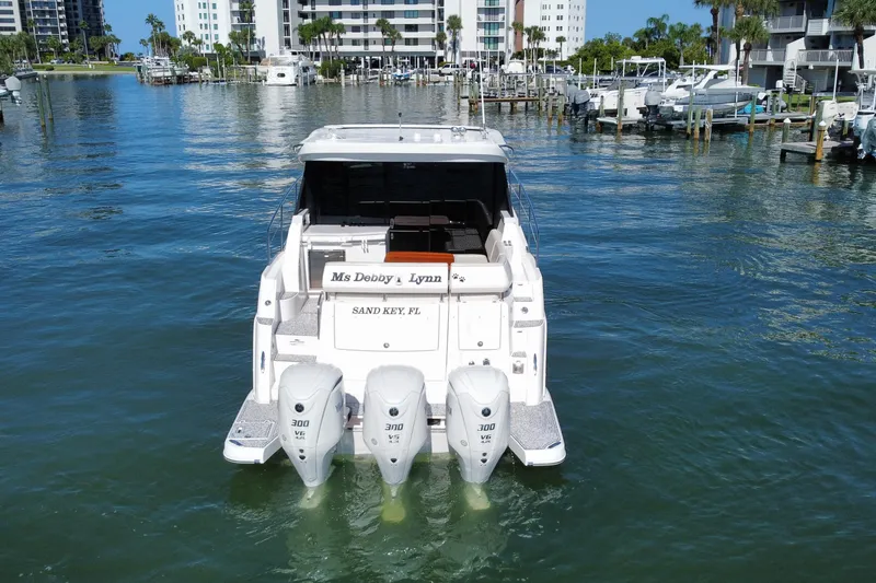 Slide: The Image of 2022 Regal 38 XO boat with triple outboard engines in a marina setting. - 6