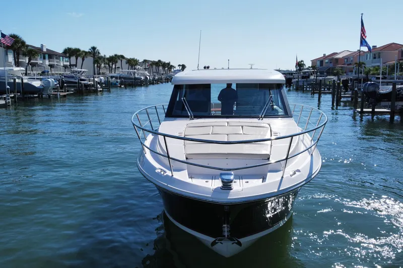 Slide: The Image of 2022 Regal 38 XO yacht cruising in a sunny marina with waterfront homes. - 8