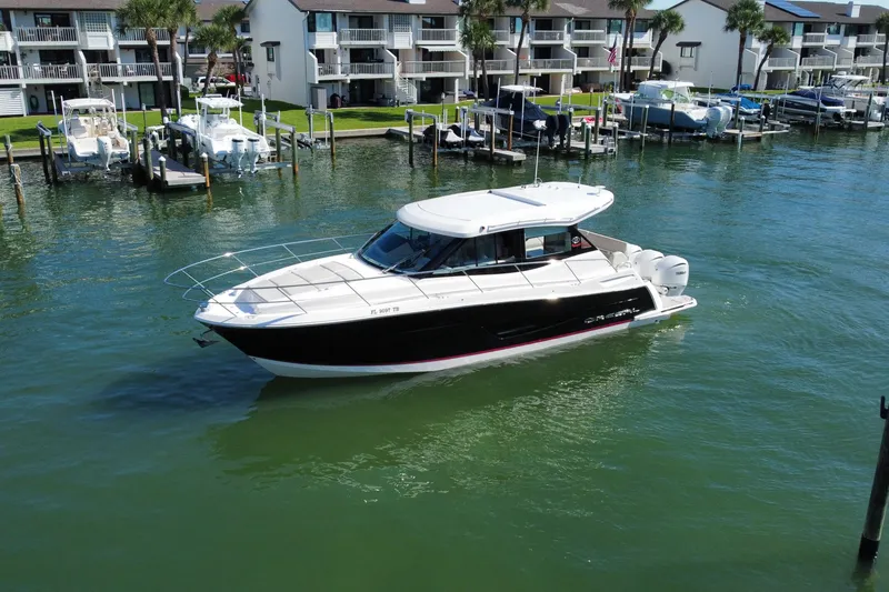 Slide: The Image of 2022 Regal 38 XO boat cruising in a marina with waterfront condos in the background. - 9