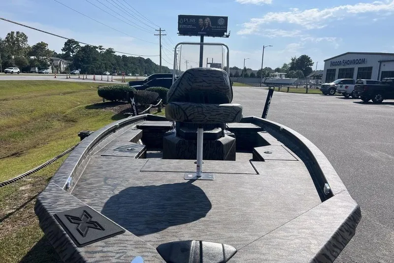Slide: The Image of 2026 Xpress H20 boat with camouflage design parked outdoors near a showroom. - 10