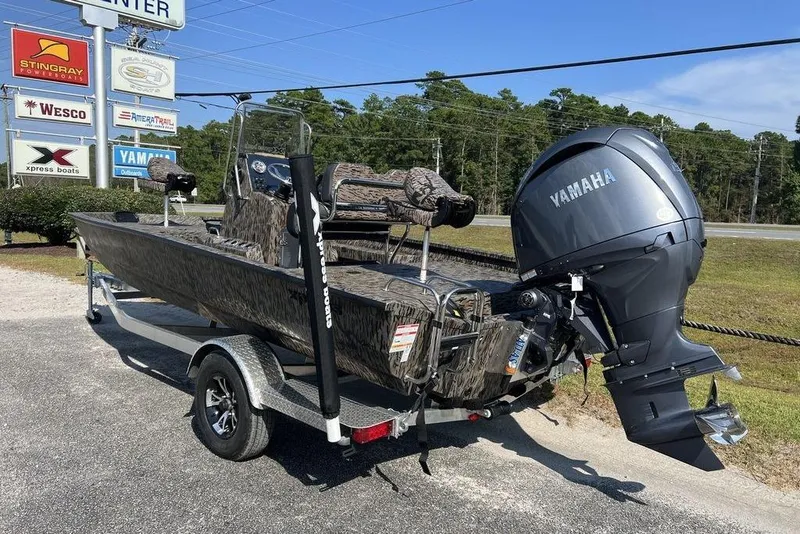 Slide: The Image of 2026 Xpress H20 boat with Yamaha engine on trailer, parked near dealership signs. - 2