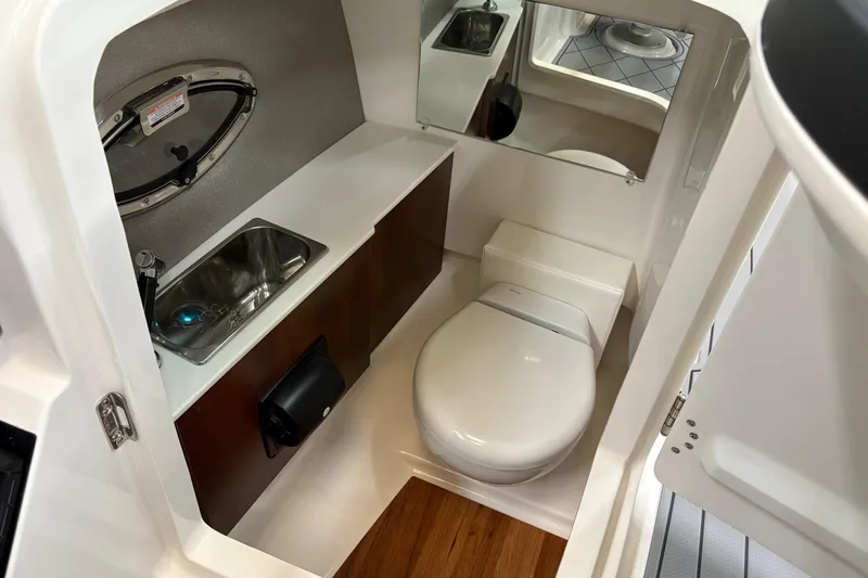 Slide: The Image of 2025 Chaparral 26 Surf boat interior bathroom with sink, toilet, and mirror. - 13